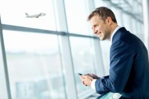 Smiling Businessman Looking Out Airport Window.